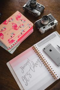 Kaboompics - Pink Floral Notebook with Two Vintage Cameras and Calendar, Wooden Desk Flat Lay
