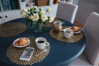 Kaboompics - Round breakfast table with white flowers, golden mats, coffee, croissant and smartphone