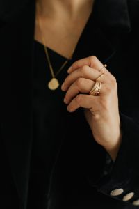 Kaboompics - Gold Necklace and Rings on Woman's Hand Against Black Blazer