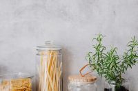 Kaboompics - Glass Pantry Jars with Pasta, Flour and Fresh Rosemary on a Neutral Counter