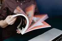 Kaboompics - Person Flipping Through a Magazine Beside a Laptop