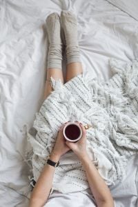 Kaboompics - Soft photo of woman on the bed with the book and cup of tea in hands