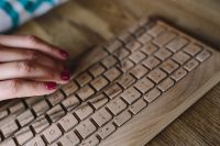 Kaboompics - Closeup of female hands typing text on a wireless wooden keyboard