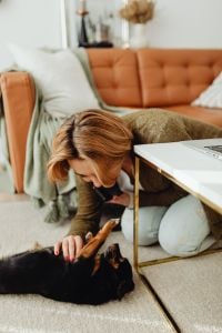 Kaboompics - Woman Bending Down to Pet Her Dog Beside the Home Office Couch