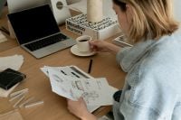 Kaboompics - Designer Reviewing Sketches with Laptop, Coffee and Interior Magazines