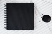 Kaboompics - Overhead Flat Lay of Black Notebook and Wooden Bird on White Marble Desk