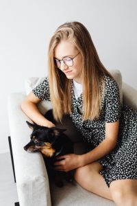 Kaboompics - Teenage Student Cuddling a Small Black-and-Tan Dog in an Armchair, Cozy Back-to-School Home Lifestyle Portrait