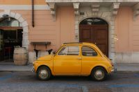 Kaboompics - Side View of a Yellow Vintage Car Beside a Palazzo Entrance in Trieste