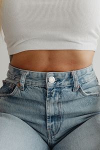 Kaboompics - White Ribbed Crop Top and Bare Midriff above High-Waisted Blue Jeans, Fashion Close-Up