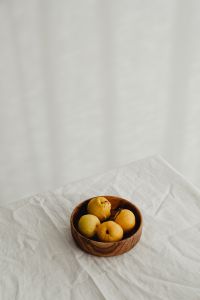 Kaboompics - Japanese Quince in a Wooden Bowl at the Bottom of a Linen Frame, Vertical Copy Space