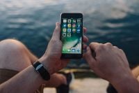 Kaboompics - Man Holding a Smartphone Over the Sea with Both Hands in View
