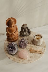 Kaboompics - Wooden Buddha, Stone Figure, Crystals, Candle, and Matchsticks On Round Marble Table