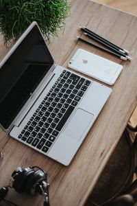 Kaboompics - Silver Acer laptop on a wooden desk with a green plant, pencils and an Apple iPhone