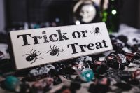 Kaboompics - Close-Up Trick-or-Treat Sign with Halloween Candy and Blurred Skull Decor