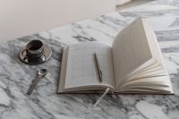 Kaboompics - Open Weekly Planner and Chrome Espresso Cup with Spoon on Marble, Wide Desk Still Life