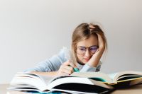 Kaboompics - Young Student Writing Notes with Open Books at Desk