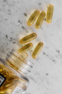 Kaboompics - Golden Capsules Spilling from a Supplement Bottle