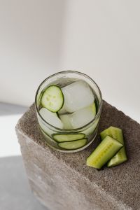 Kaboompics - Close-Up Cucumber and Lime Detox Water with Ice on a Rough Stone Pedestal, High-Angle Summer Drink Still Life