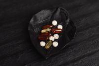 Kaboompics - Mixed Vitamins and Tablets on a Black Leaf Against a Dark Background