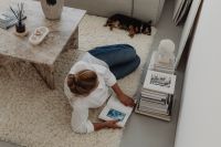 Kaboompics - Woman Sitting on a Rug with Books, a Dog and a White Bust