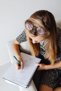Kaboompics - Close-Up of Teen Girl in Round Glasses Writing Study Notes