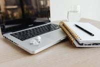 Kaboompics - Laptop, AirPods, Notebook and Glass of Water on Desk