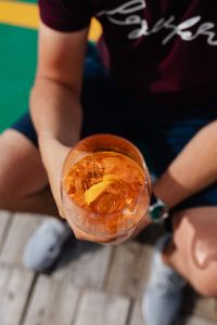 Kaboompics - Seated Person Holding a Drink by the Coast, Cropped View