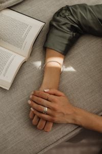 Kaboompics - Ringed Hands Resting on an Open Book on a Sofa