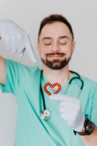 Kaboompics - Doctor Presenting Red Heart Prop in Scrubs