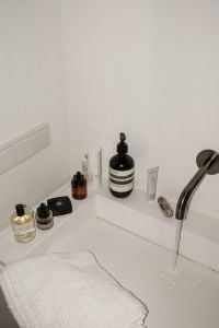 Kaboompics - Bathroom Sink with Running Water, Towel and Skincare Products