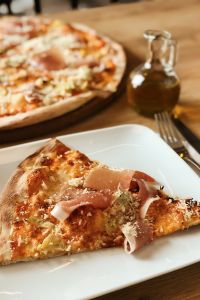Kaboompics - Pizza with Prosciutto on the white plate