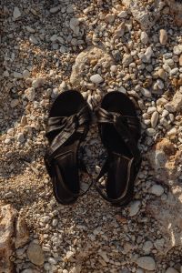 Kaboompics - Black Leather Knot Sandals in a Pebble Beach Flat Lay