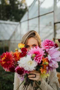 Kaboompics - Woman Looking Through Dahlias In Glasshouse
