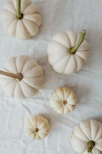 Kaboompics - Overhead Flat Lay of Four White Mini Pumpkins on Linen
