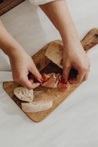 Kaboompics - Hands Arranging Prosciutto on Rustic Bread