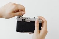 Kaboompics - Back of a 35mm Film Camera Held in Both Hands on White