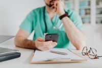 Kaboompics - Doctor Thinking While Holding Smartphone at Desk