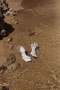 Kaboompics - White Ankle-Strap Heels Resting in Shallow Shore Water