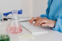 Kaboompics - Scientist Typing Research Data Beside Laboratory Glassware