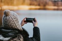 Kaboompics - Woman in a Knit Beanie Photographing a Winter Lake with Her Smartphone