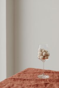 Kaboompics - Stemmed Glass Filled with Coconut Truffles on Rust Cloth, Vertical Dessert Background with Copy Space