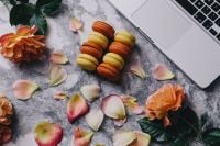Kaboompics - Colorful Macarons and Scattered Rose Petals beside a Laptop on Marble