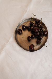 Kaboompics - Dark Cherries on a Wooden Plate on White Bedding