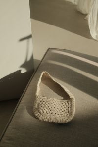 Kaboompics - Vertical Beige Crochet Bag on a Gray Chair with Strong Sunlight and Copy Space