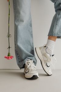 Kaboompics - Light Blue Wide-Leg Jeans and White Sneakers beside a Long-Stem Flower, Studio Detail
