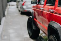 Kaboompics - Red Jeep Cherokee Along a Wet City Sidewalk with Copy Space