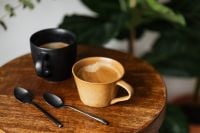 Kaboompics - Two Coffee Cups and Spoons on a Round Wooden Table with Greenery