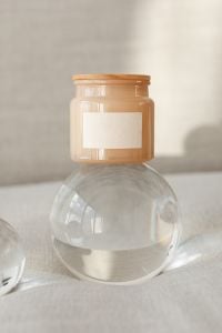 Kaboompics - Amber Candle Label Mockup Balanced on a Clear Glass Sphere