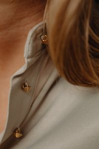 Kaboompics - Close-Up of Gold Buttons and Earring on Tan Silk Shirt, Minimal Fashion Jewelry Detail