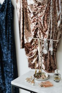 Kaboompics - colored sequin dresses hands on the white wall, marble table with Jewelry